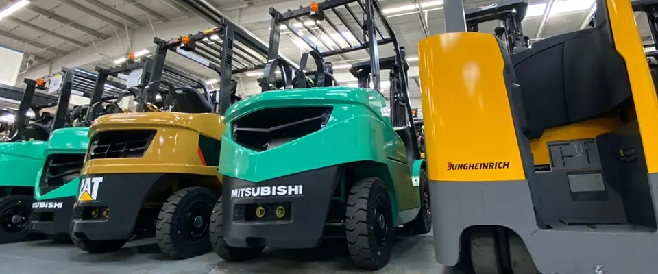 Row of teal and yellow used forklifts